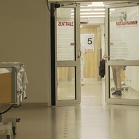 Der Gang zu einer Notaufnahme eines Krankenhauses. Direkt vor dem Eingang zur Notaufnahme steht ein leeres Krankenbett.