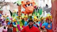 Mehrere Menschen mit Giraffenhüten laufen auf dem Umzug mit
