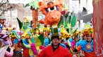 Mehrere Menschen mit Giraffenhüten laufen auf dem Umzug mit