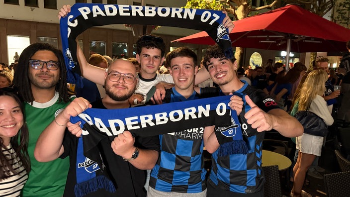 Mehrere Zuschauer freuen sich in der Paderborner Innenstadt über den Aufstieg des SC Paderborn.