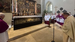 Mehrere Geistliche schauen auf einen mit Reliquien gefüllten Schrein