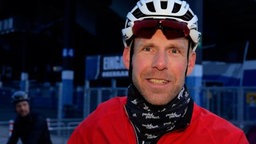 Das Bild zeigt einen Mann der einen Fahrradhelm trägt und lächelt.