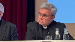 Erzbischof Udo Markus Benz hört den Gläubigen aus dem Publikum aufmerksam zu.