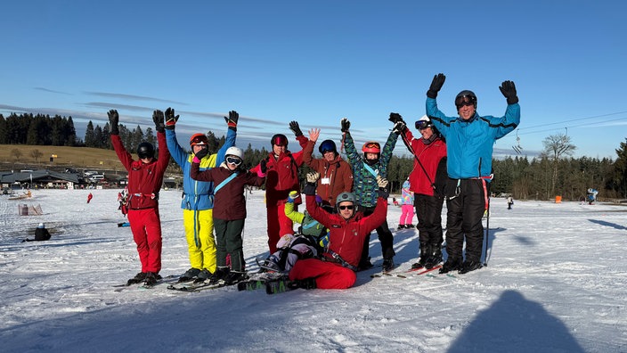 Jubelnde Menschen stehen auf einer Skipiste
