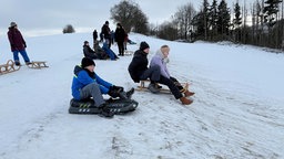 Kinder sitzen auf Schlitten