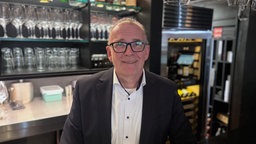 Bernd Tönsing steht lächelnd vor einer Bar