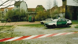 Der Tatort des Raubmordes an Eberhard Büker in 1990. Hinter einem Flatterband steht ein alter Polizeiwagen auf einem Spielplatz.