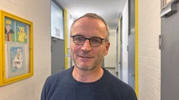 Ein Mann mit Brille steht in einem Flur