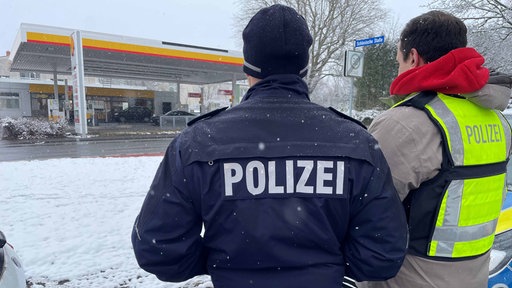 Zwei Polizeibeamte vor einer Tankstelle