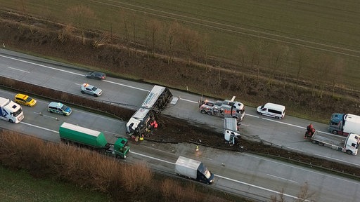 Eine Drohnenaufnahme des verunglückten LKW, daneben Einsatzkräfte und Einsatzfahrzeuge