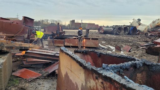 Zwei Männer bearbeiten Metallteile mit Schweißgeräten auf einer Baustelle