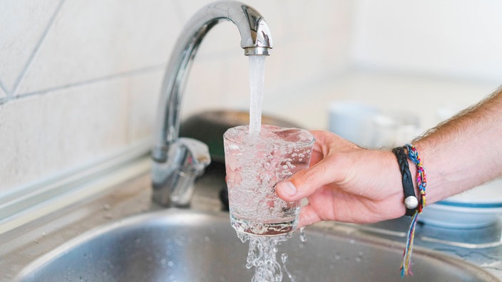 Wasser aus einem Wasserhahn fliesst in ein Glas
