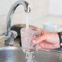 Wasser aus einem Wasserhahn fliesst in ein Glas