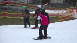 Eine Snowboardfahrer:in auf der Skipiste. Dahinter zwei Skifahrer:innen.