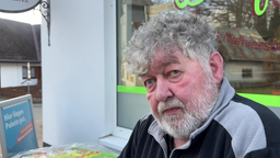 Peter Lauber sitzt vor dem Dorfladen und schaut in die Kamera.