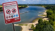 Montage: Schild zum Badeverbot, dahinter Luftbild vom Rhein 