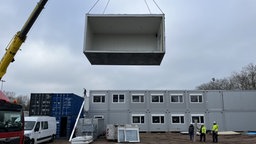 Auf dem Bild ist ein Container an einem Bagger zu sehen