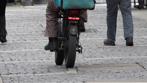Ein Lieferfahrer auf einem motorisierten Bike auf der Straße