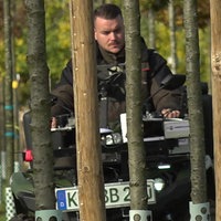 Mann auf Traktor hinter Bäumen 