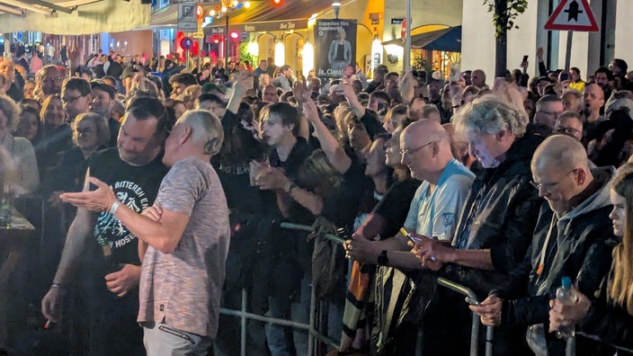 Hunderte Fans der Toten Hosen stehen vorm Ratinger Hof in Düsseldorf vor Absperrung. Sie hören dem Konzert zu, das drinnen stattfindet. 