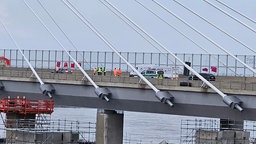 Menschen in Warnwesten und ein Polizeiauto stehen auf der Leverkusener Rheinbrücke