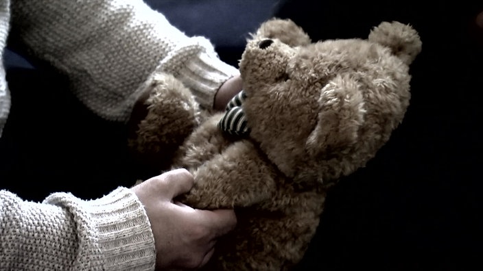 Teddybär wird von Kinderhänden gehalten