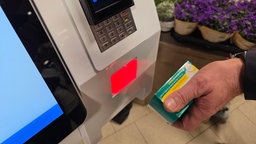Eine Hand hält eine Arzneipackung unter einen Scanner