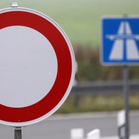 Im Vordergrund ist ein Sperrschild, dahinter ein Autobahnschild zu sehen 
