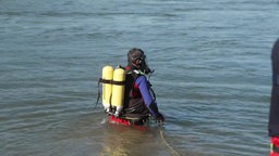 Ein Taucher mit Sauerstoffflaschen auf dem Rücken sucht im Rhein nach dem Vermissten.