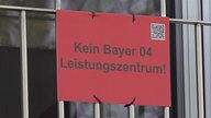 Ein rotes Schild mit der Aufschrift "Kein Bayer 04 Leistungszentrum!"