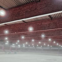 Eine leere Eisfläche in einer Halle. Über dem Eisfeld liegt Nebel.