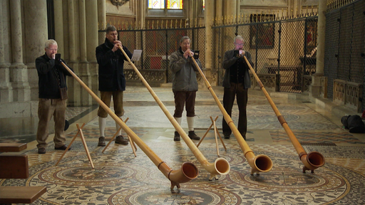 Vier Männer in traditionellen Lederhosen spielen Alphorn im Kölner Dom 