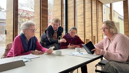Das Bild zeigt eine Frau, die den Teilnehmerinnen Smartphones erklärt.