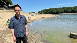 Mann steht am Seeufer