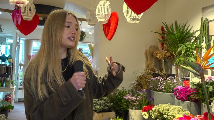 Eine Frau steht mit einem Mikrofon in einem Blumenladen