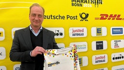 MMP-Geschäftsführer Christian Okon zeigt das bunte Sondertrikot zum diesjährigen Marathon