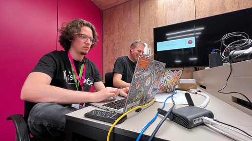 Zwei junge Männer sitzen vor ihren Laptops
