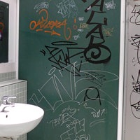 Eine Schultoilette, deren Wände mit Graffiti beschmiert sind.