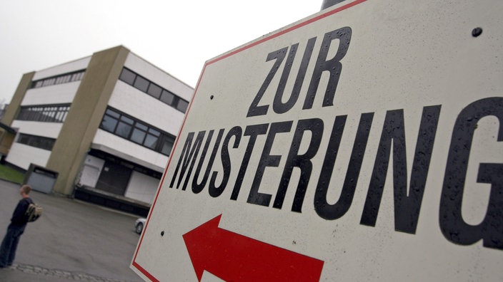 Schild mit der Aufschrift zur Musterung vor einem mehrstöckigen Gebäude