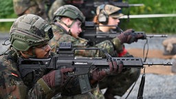 Soldaten in Tarnkleidung zielen mit Waffen