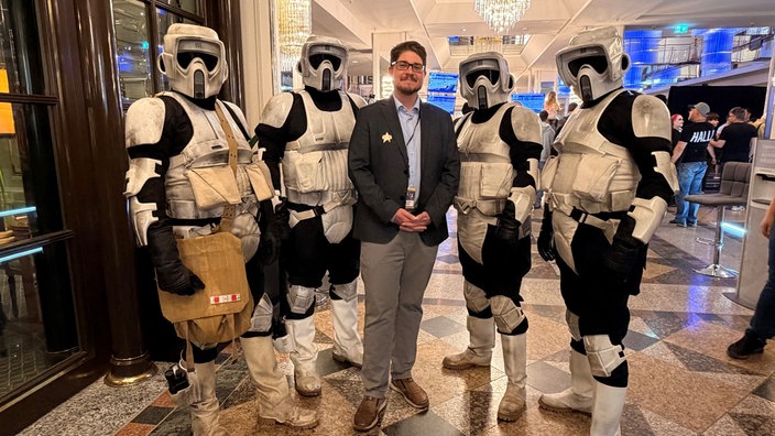 Vier Menschen in Stormtrooper-Kostümen, in der Mitte ein Mann im Jackett