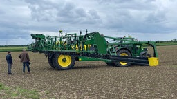 Zwei Männer stehen neben einer landwirtschaftlichen maschine auf einem Feld