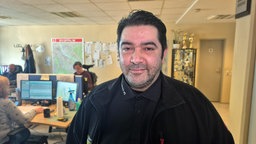 Robar Saado, ein Mann mit dunklen Haaren und schwarzem Pulli, steht in einem Büro.
