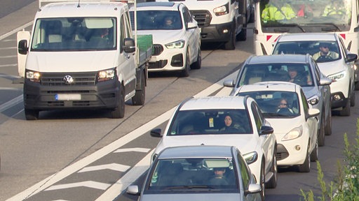 Viele Fahrzeuge stehen dicht gedrängt im Stau auf der Asphaltbahn einer Autobahn.