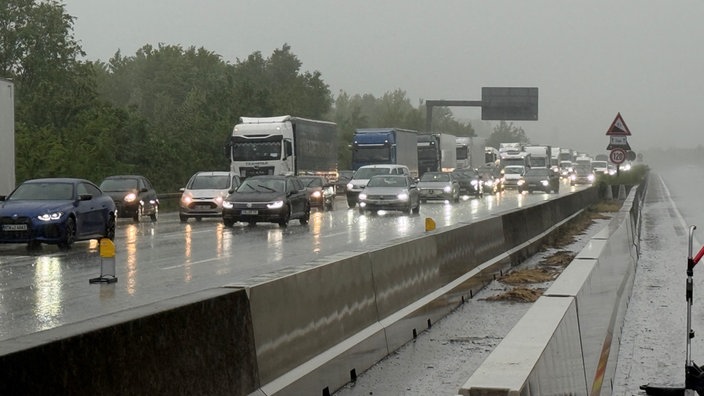 Pkw und Lkw stehen im Stau auf der regennassen Fahrbahn der A3
