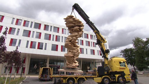 Tony Craggs Skulptur wird mit einem Kran vor das Bonner Uniklinikum getragen.