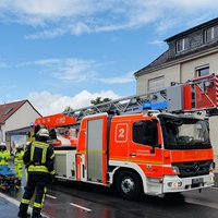 Feuerwehrleute in Einsatzkleidung vor einem Feuerwehrauto mit eingeklappter Leiter