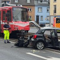 Nach dem Unfall ist der Pkw stark beschädigt und Einzelteile liegen auf der Fahrbahn und den Schienen.