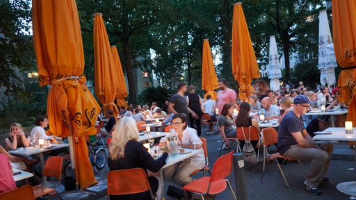 Menschen sitzen im Außenbereich einer Bar.