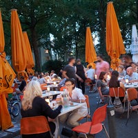 Menschen sitzen im Außenbereich einer Bar.